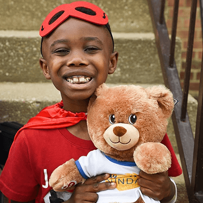 child in cape and mask hugging bear – Build-A-Bear Foundation