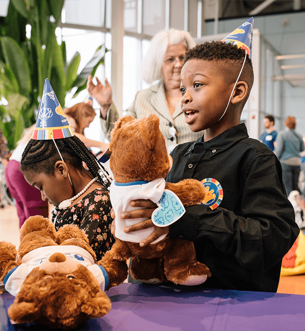 child with bear and party hat – Build-A-Bear Foundation